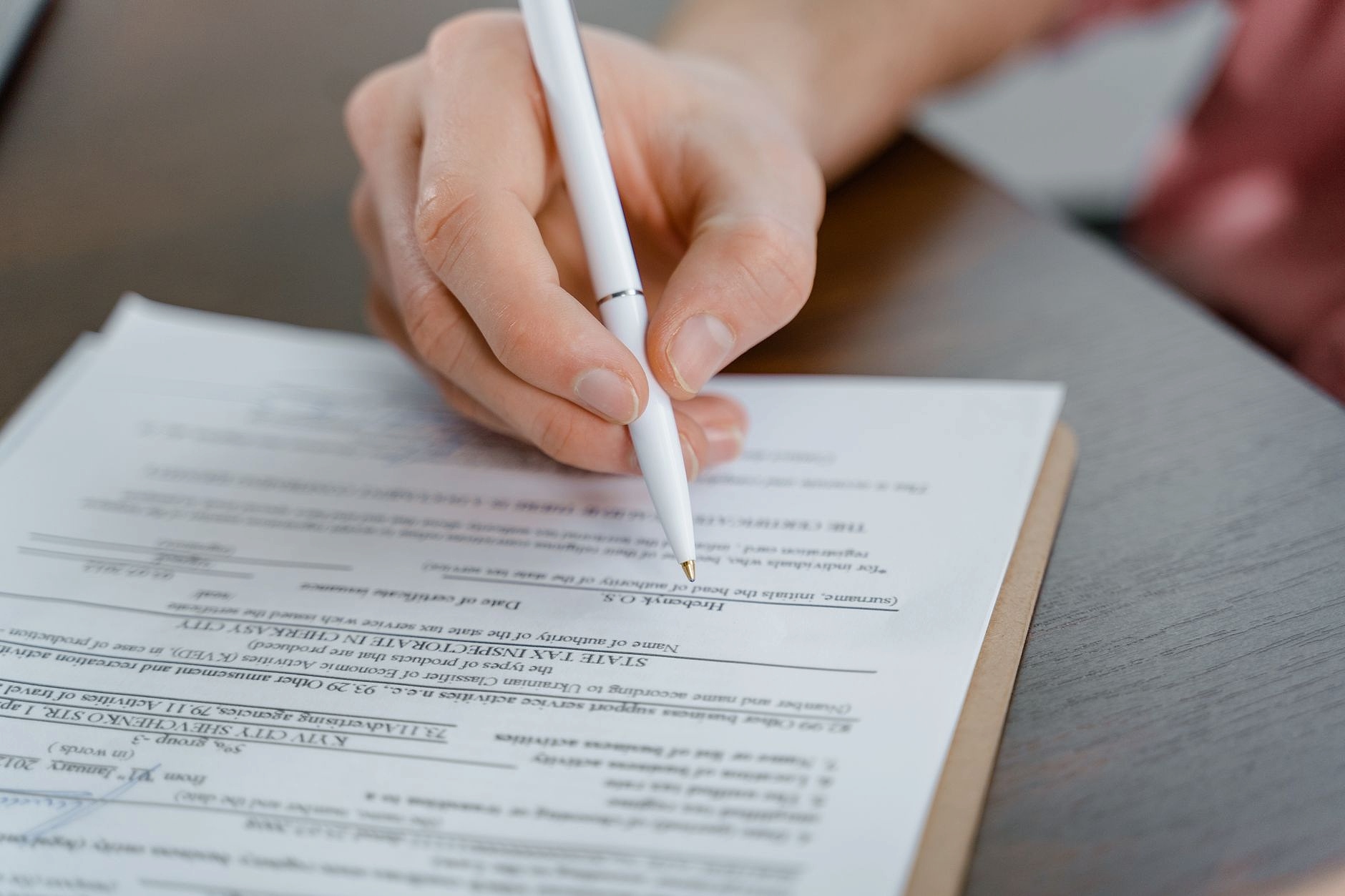 Person filling out business registration documents at desk